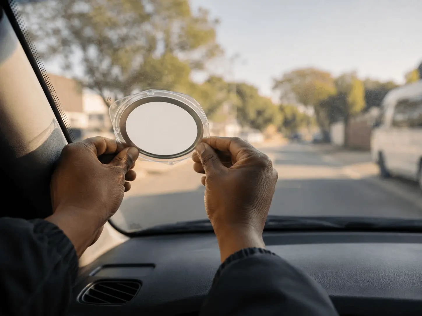 Close-up of a fresh licence disc being fitted into its holder on a windscreen